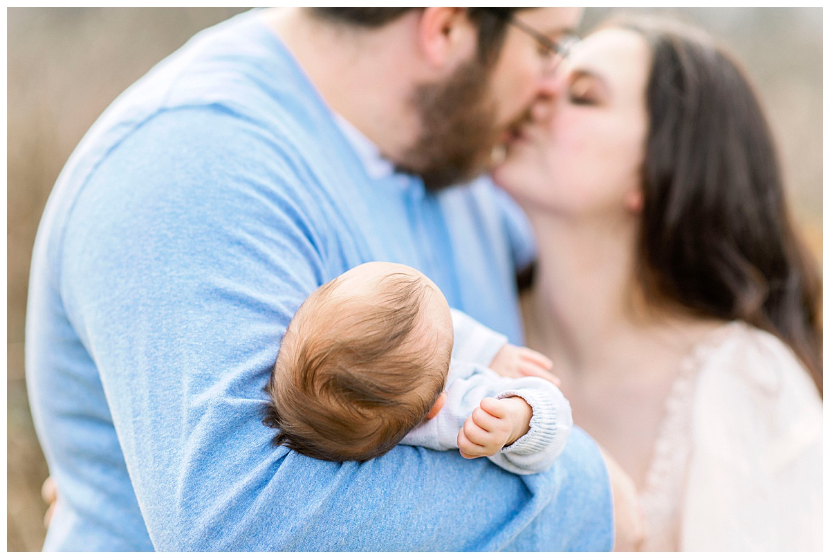 parents kissing holding newborn doulas greensboro nc